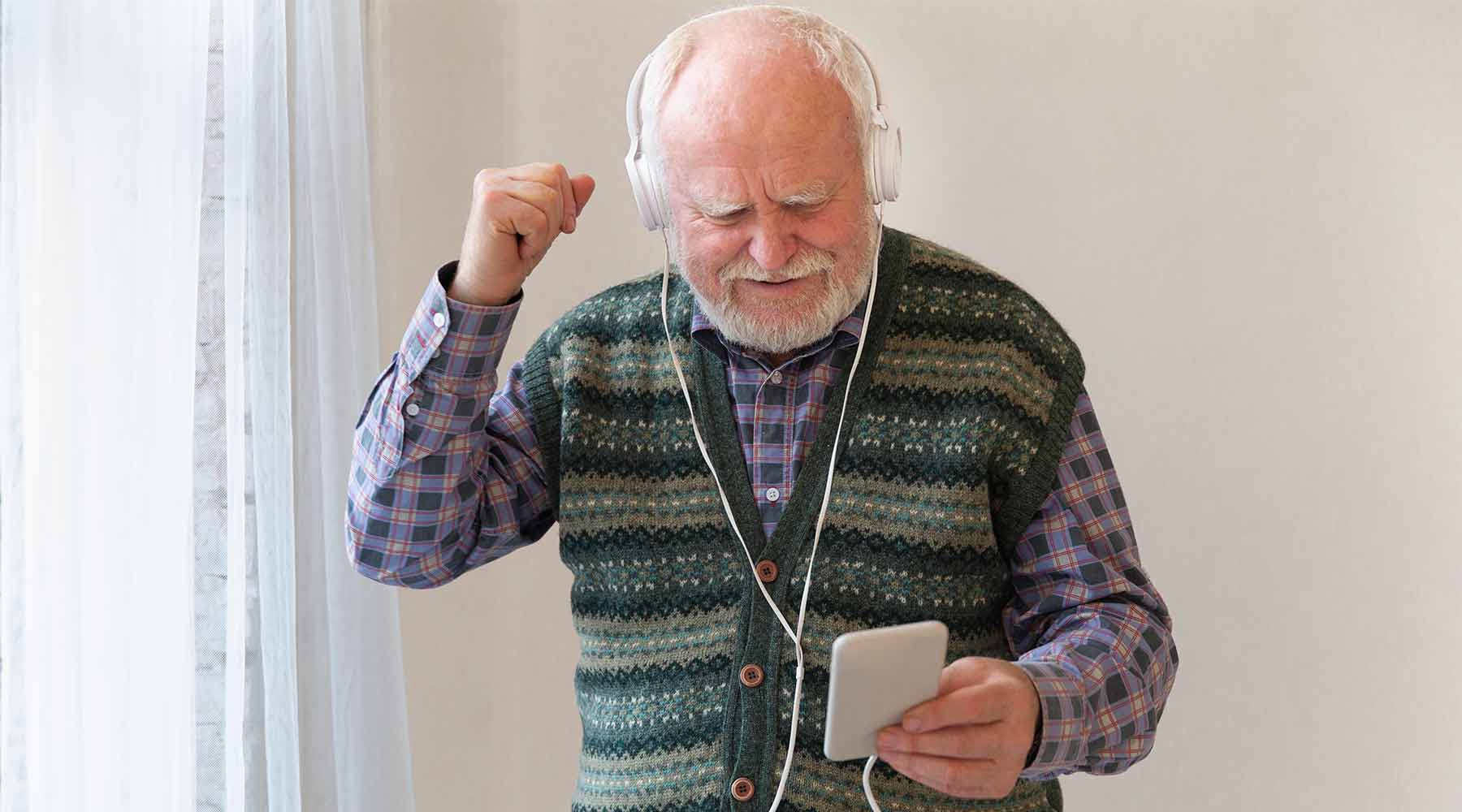 Anciano escuchando música en smartphone.