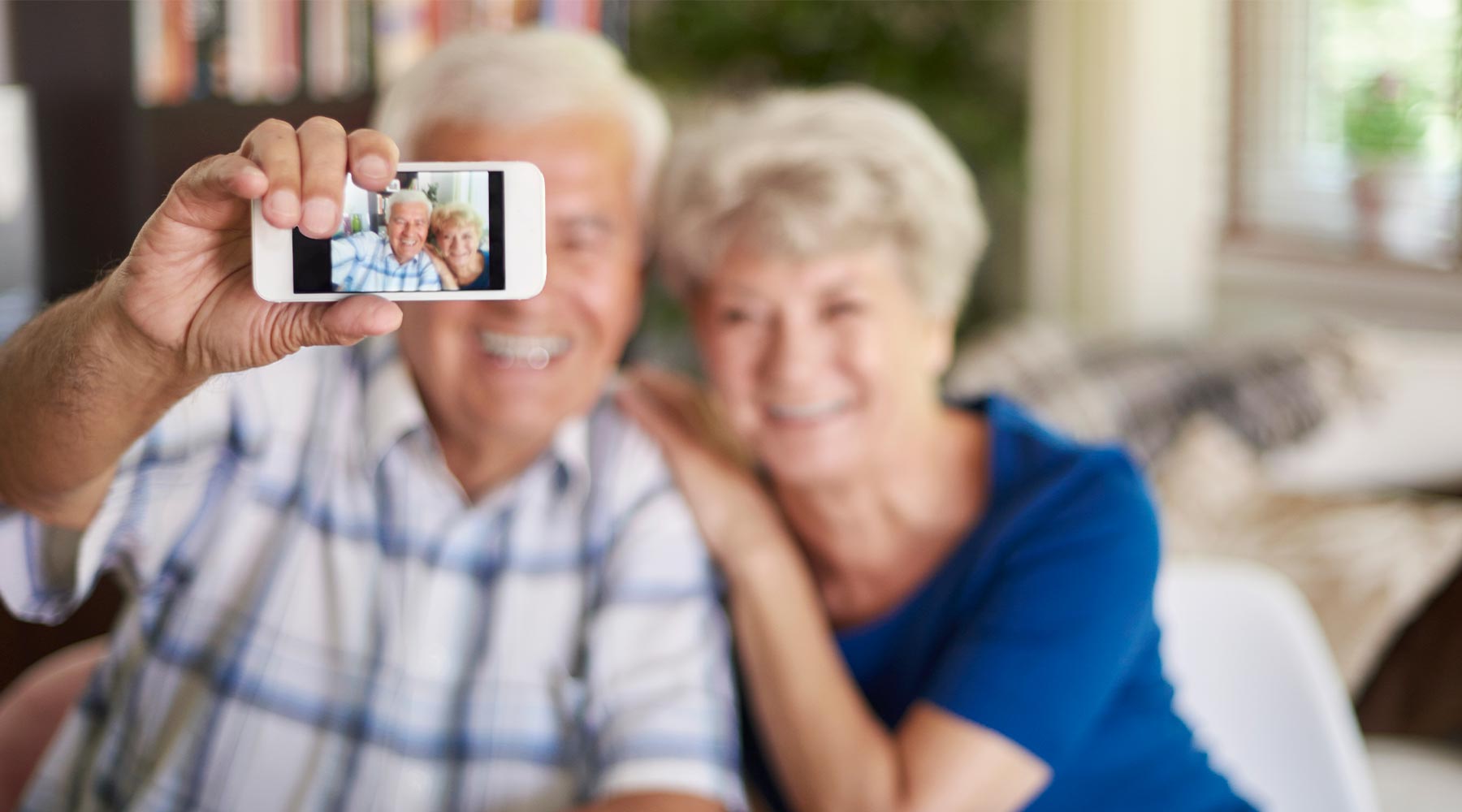 Pareja de personas mayores tomándose un selfie con un teléfono móvil.