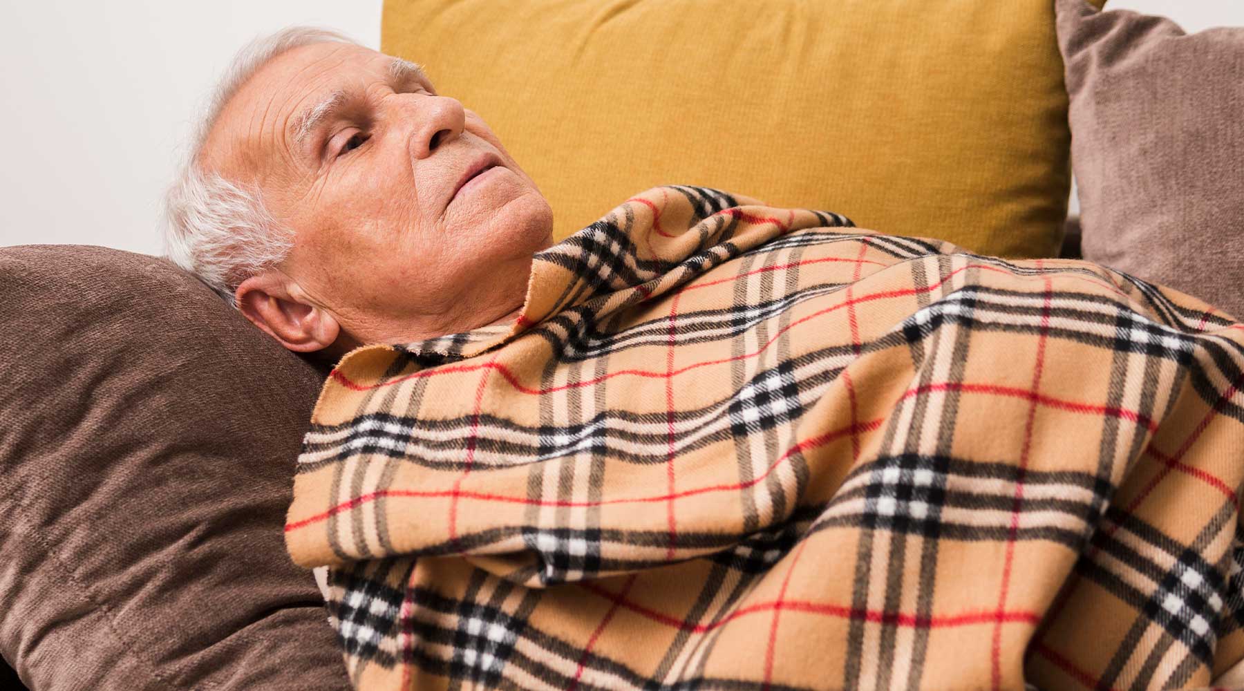 Anciano con neumonía acostado en su sofá.