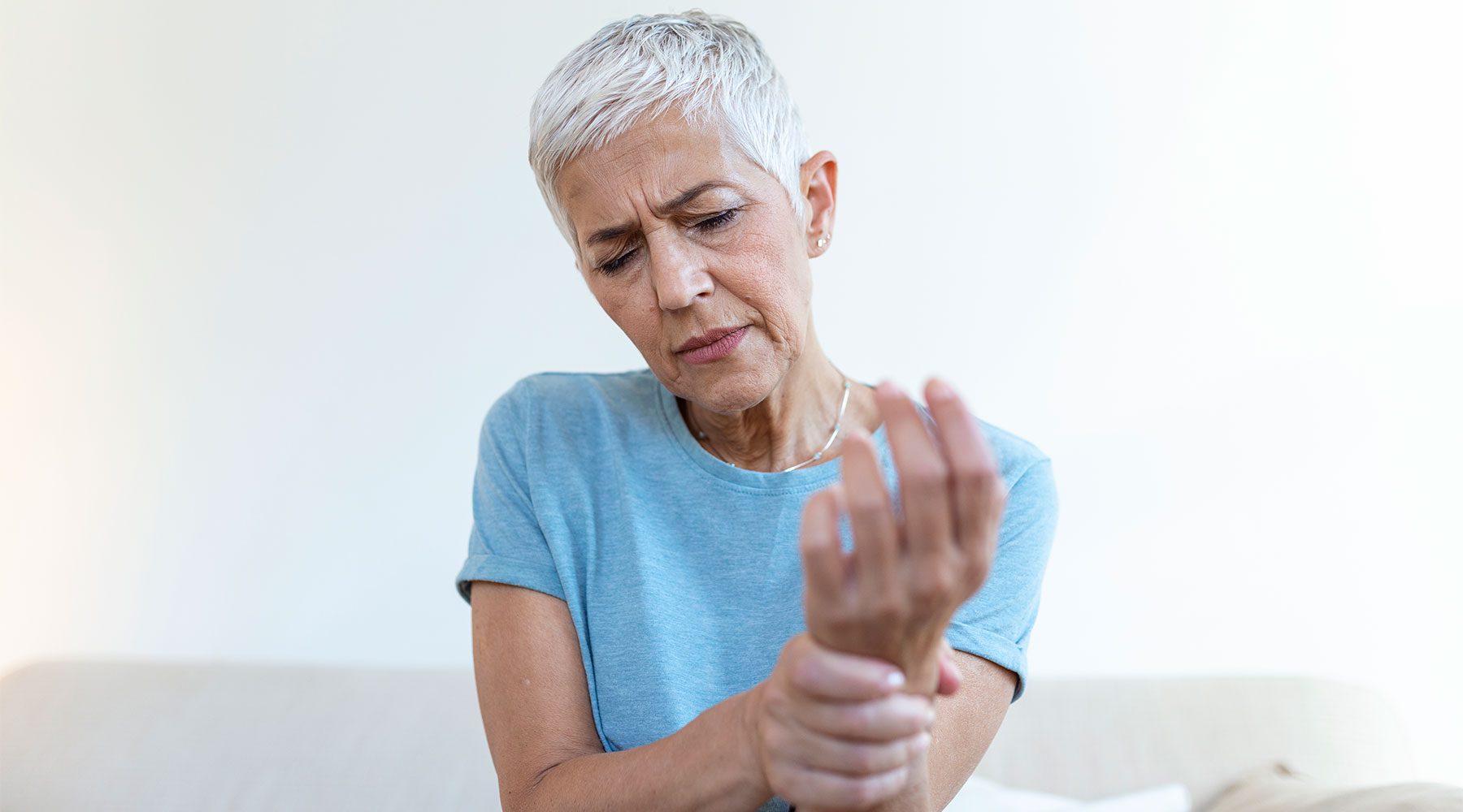 Anciana en casa que sufre dolor en la mano por artritis.