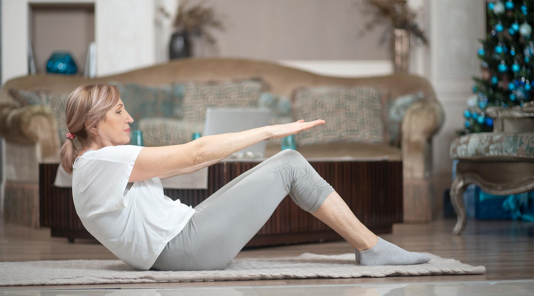 Mujer de más de 50 años haciendo yoga en casa. Tendida en el suelo realizando ejercicios asanas. 