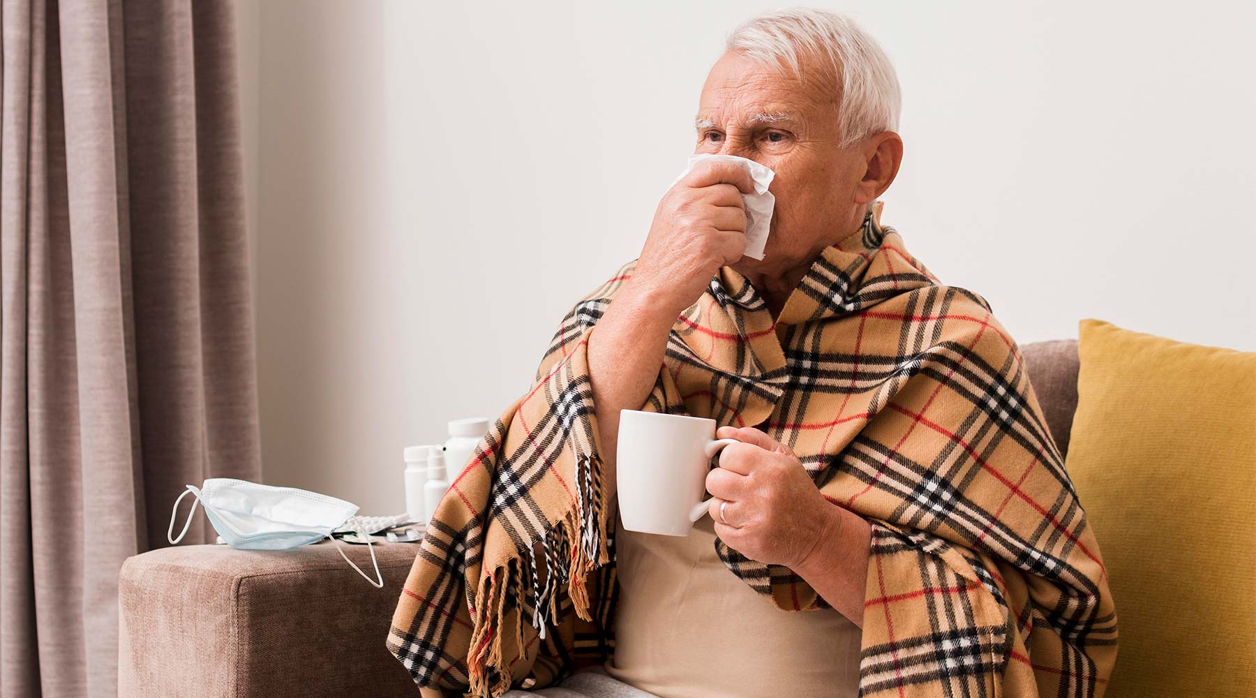 Anciano sonándose la nariz con una taza en la mano.