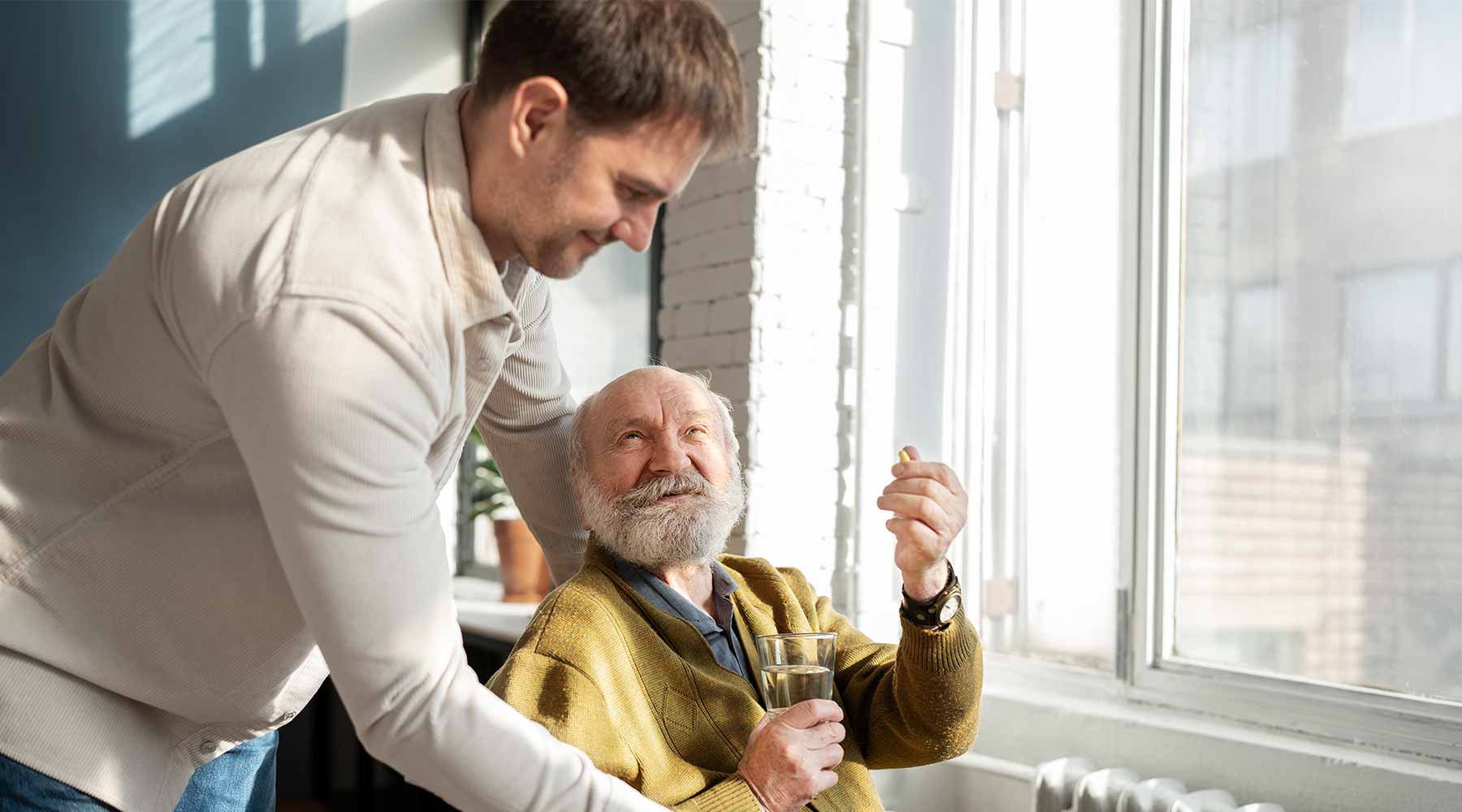 Cuidador de ancianos controlando la medicación de paciente mayor.