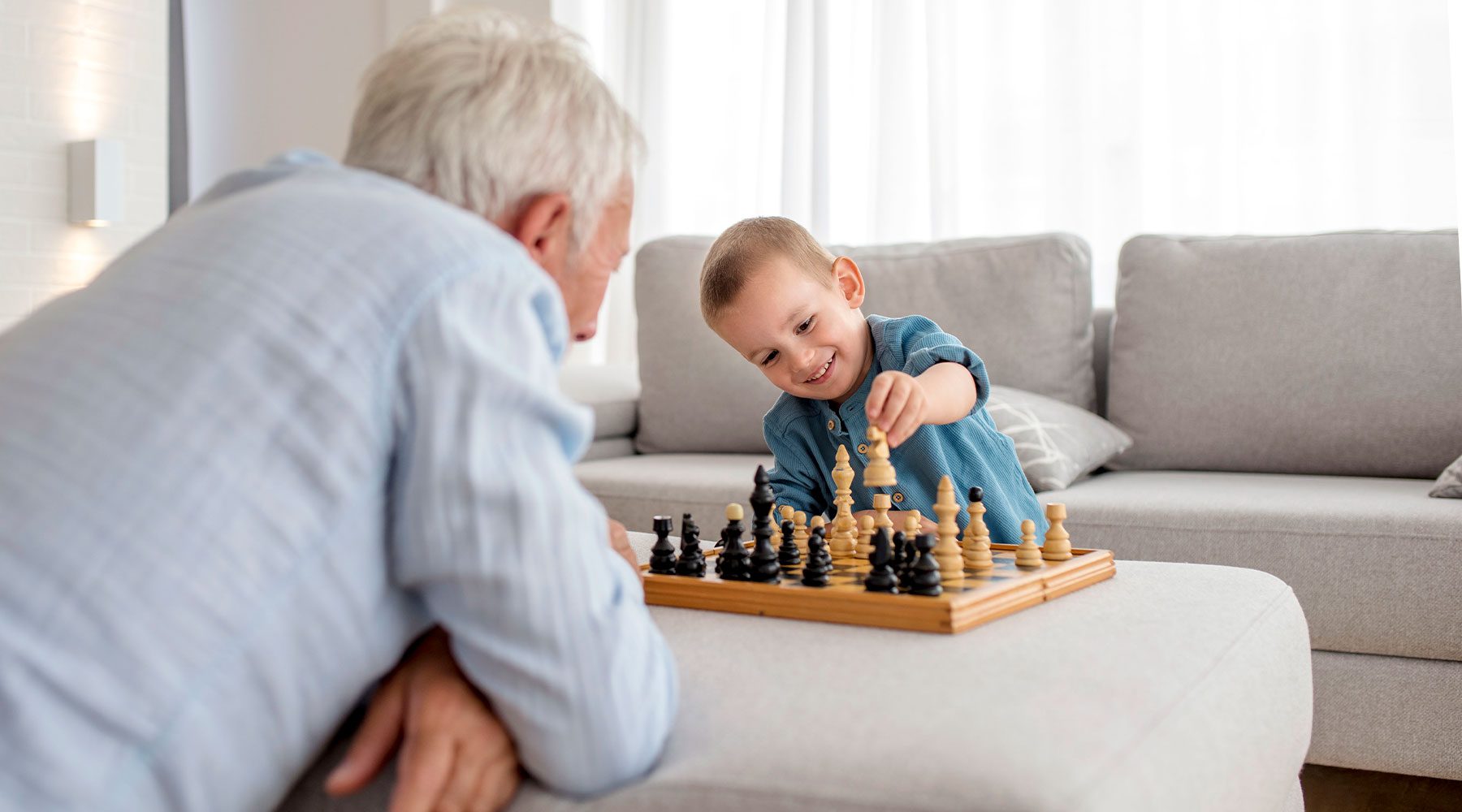 Abuelo jugando a juegos para ancianos en casa con su adorable nieto.